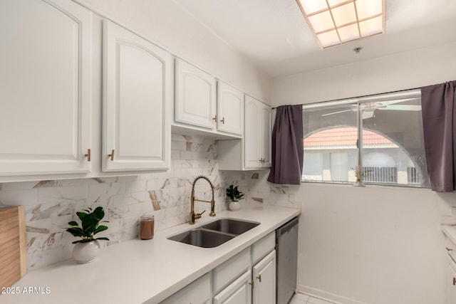 kitchen featuring a sink, dishwasher, light countertops, white cabinetry, and tasteful backsplash