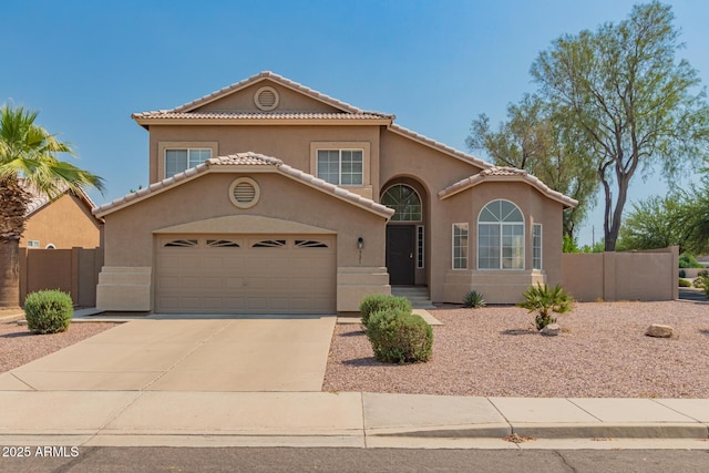 mediterranean / spanish home with stucco siding, concrete driveway, fence, and an attached garage