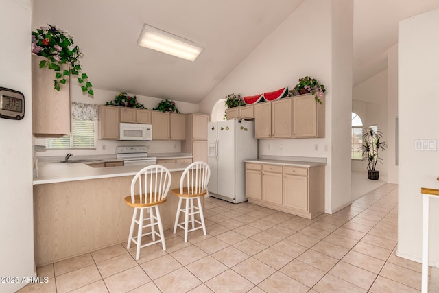 kitchen with white appliances, lofted ceiling, a peninsula, light countertops, and a sink