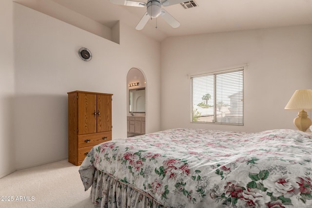 bedroom with light colored carpet, vaulted ceiling, arched walkways, and a ceiling fan