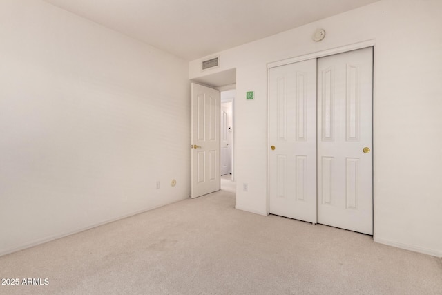 unfurnished bedroom featuring light carpet and a closet