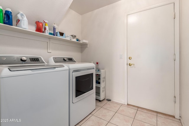 clothes washing area featuring washer and clothes dryer and light tile patterned flooring