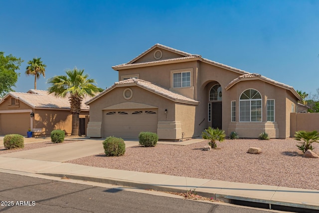 mediterranean / spanish-style home with stucco siding, driveway, an attached garage, fence, and a tile roof