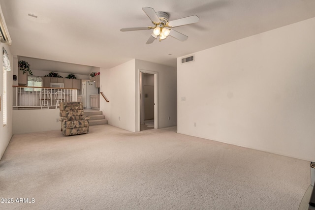 unfurnished living room featuring ceiling fan, carpet flooring, and stairway