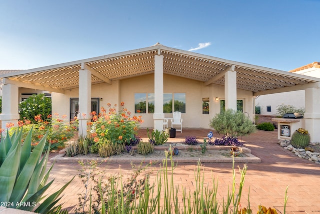 rear view of property with a fireplace, a pergola, and a patio