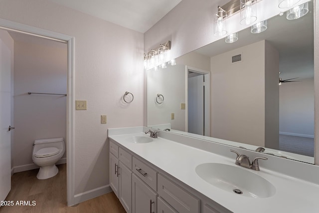 bathroom featuring toilet, ceiling fan, vanity, and hardwood / wood-style floors