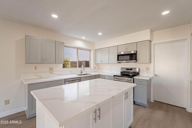 kitchen with a kitchen island, stainless steel appliances, light hardwood / wood-style flooring, and sink