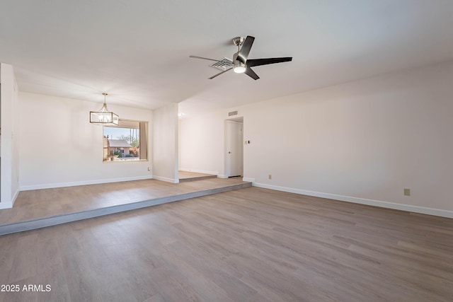 unfurnished room with ceiling fan with notable chandelier and hardwood / wood-style floors