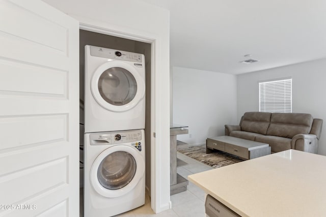 clothes washing area featuring stacked washer / drying machine and light tile patterned floors