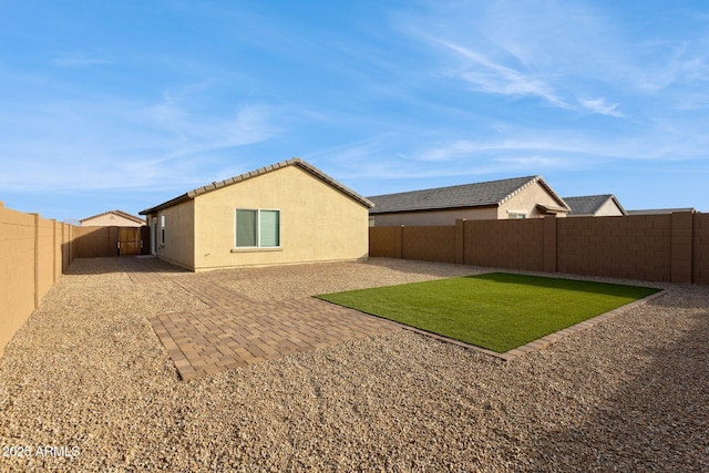 back of house with a patio and a lawn