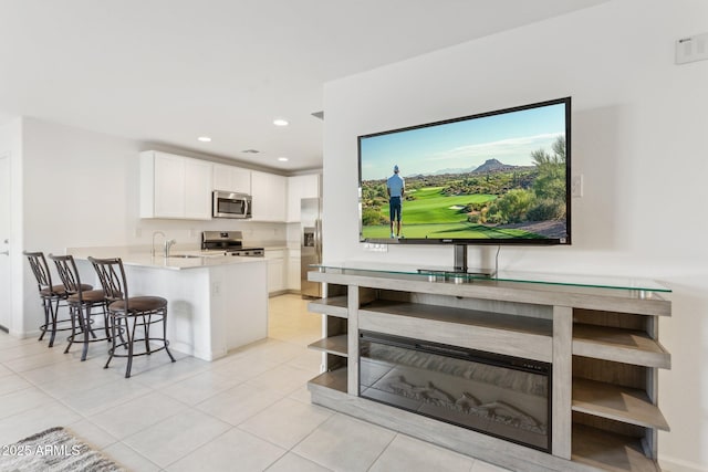 kitchen featuring a kitchen bar, sink, white cabinetry, kitchen peninsula, and stainless steel appliances