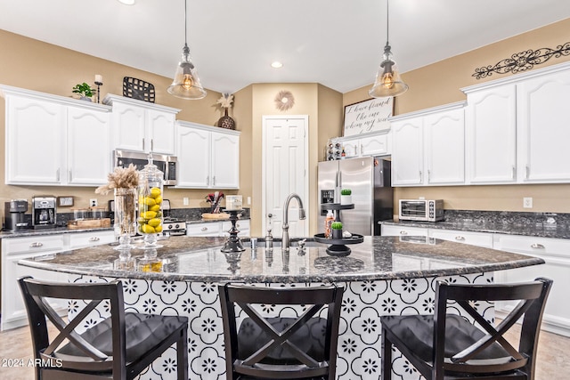 kitchen with dark stone counters, a kitchen island with sink, and stainless steel appliances