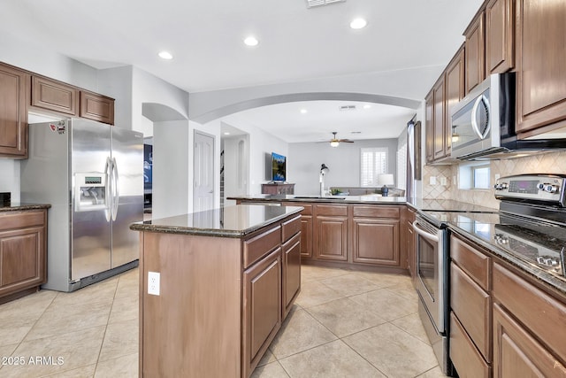 kitchen featuring light tile patterned flooring, sink, dark stone counters, a center island, and stainless steel appliances