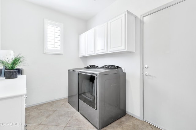 washroom with cabinets, light tile patterned floors, and washer and clothes dryer