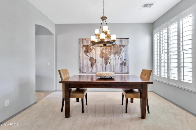 carpeted dining room with an inviting chandelier