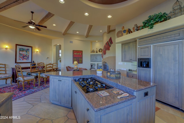 kitchen with beamed ceiling, paneled fridge, gas stovetop, and a kitchen island