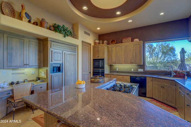 kitchen featuring sink, a tray ceiling, a breakfast bar area, and black appliances