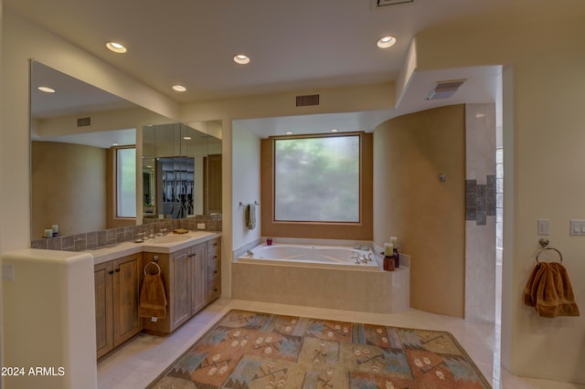 bathroom with tiled bath, tile patterned flooring, and vanity