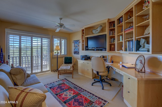 carpeted office featuring ceiling fan and built in desk