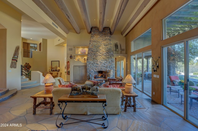 living room featuring a stone fireplace, a towering ceiling, and beamed ceiling