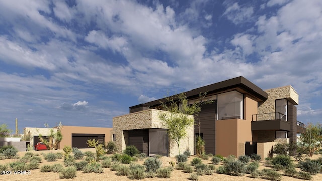 back of property featuring an attached garage, stone siding, a balcony, and stucco siding