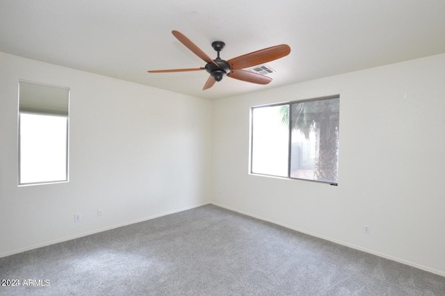 carpeted spare room featuring plenty of natural light and ceiling fan