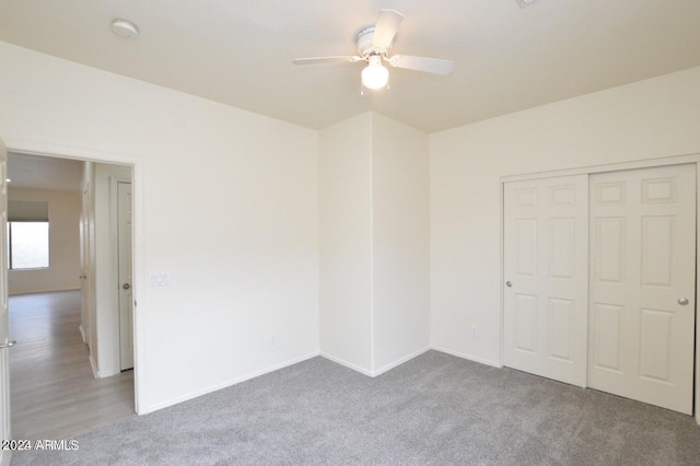 unfurnished bedroom with ceiling fan, light colored carpet, and a closet