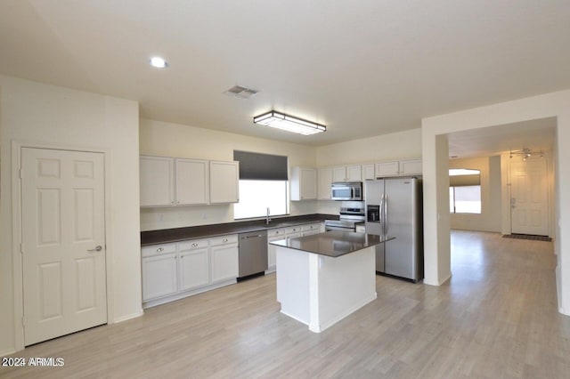 kitchen with white cabinetry, sink, a center island, stainless steel appliances, and light wood-type flooring