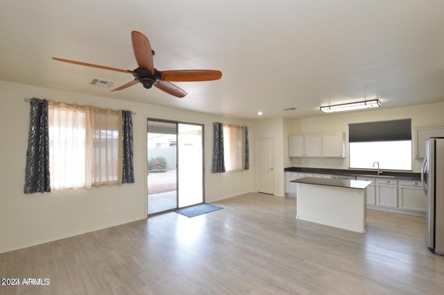 kitchen featuring stainless steel refrigerator, white cabinetry, sink, and a kitchen island