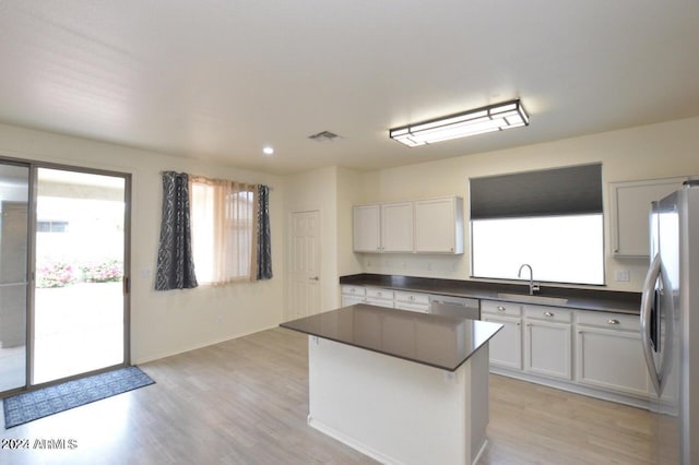 kitchen with a center island, sink, light wood-type flooring, appliances with stainless steel finishes, and white cabinetry