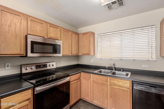 kitchen with stainless steel appliances, a sink, dark countertops, and light brown cabinets