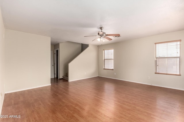 unfurnished living room with a ceiling fan, wood finished floors, and baseboards
