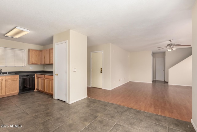 kitchen featuring dishwasher, a sink, open floor plan, a ceiling fan, and baseboards