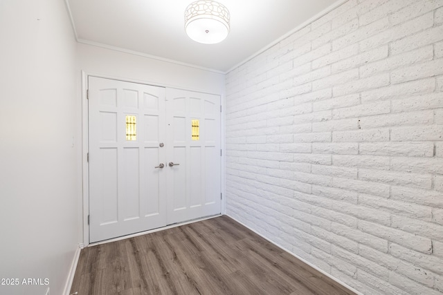 foyer featuring hardwood / wood-style flooring, brick wall, and crown molding