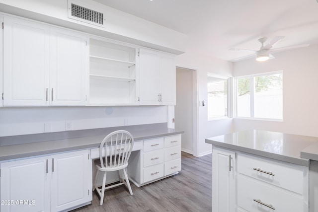 office area with built in desk, ceiling fan, and light hardwood / wood-style floors