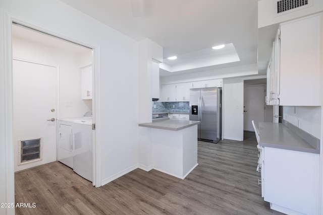 kitchen with stainless steel fridge with ice dispenser, white cabinetry, separate washer and dryer, dark hardwood / wood-style floors, and a tray ceiling