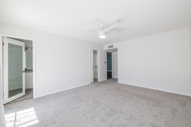 unfurnished bedroom with ceiling fan, connected bathroom, and light carpet