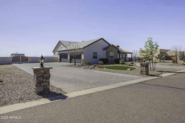 view of front of home with fence, stucco siding, decorative driveway, a garage, and a gate