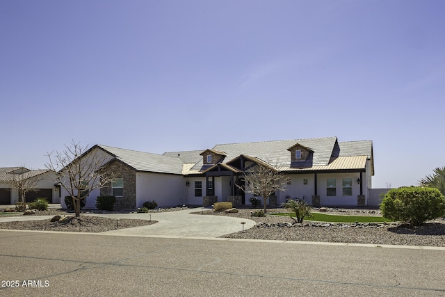 view of front facade with stone siding, stucco siding, driveway, and metal roof