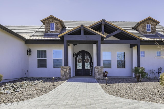 property entrance with french doors, stone siding, and stucco siding