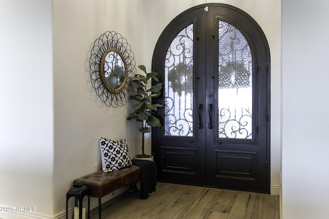 foyer featuring wood finished floors, french doors, and arched walkways