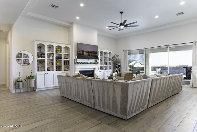 living room with visible vents, recessed lighting, light wood-style floors, and a glass covered fireplace