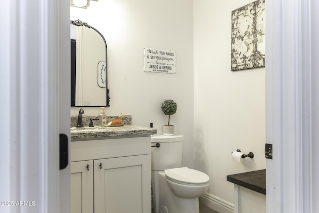 bathroom with vanity, toilet, and baseboards