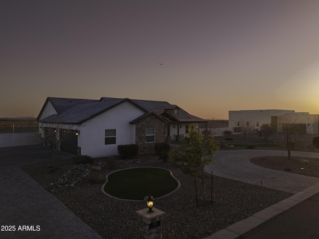 view of front of house with decorative driveway, stone siding, and stucco siding