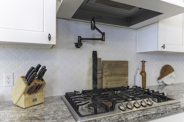 room details with stainless steel gas cooktop, range hood, and white cabinetry