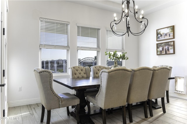 dining space featuring a notable chandelier, a healthy amount of sunlight, baseboards, and light wood finished floors