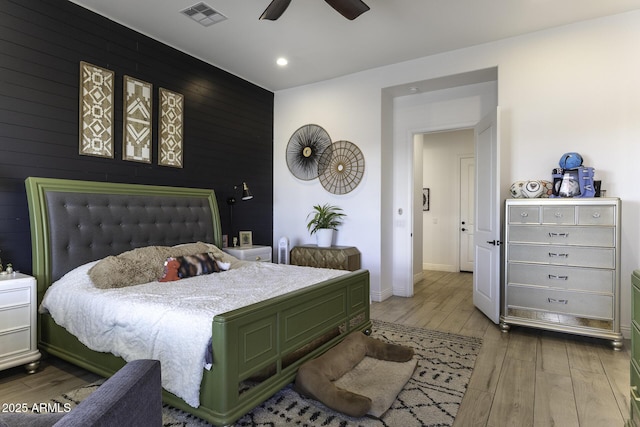 bedroom featuring visible vents, an accent wall, baseboards, recessed lighting, and wood finished floors