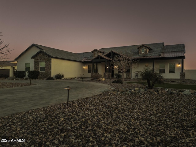 view of front of house featuring stone siding, driveway, and stucco siding