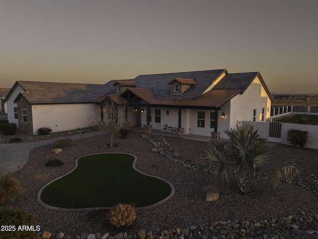 view of front of house with a patio area, fence, and stucco siding