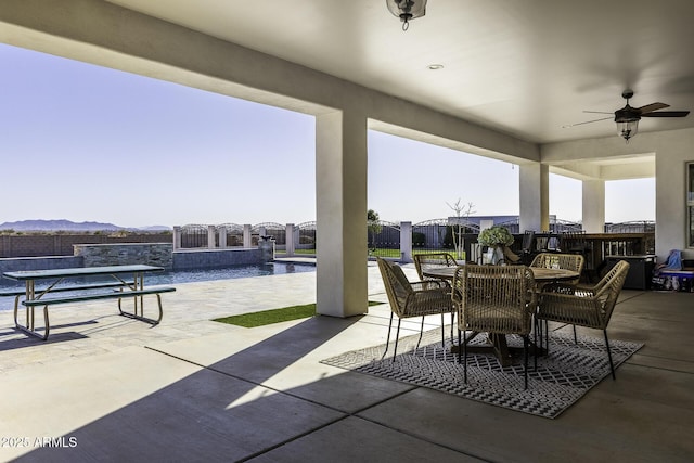 view of patio / terrace featuring a mountain view, outdoor dining space, and a ceiling fan